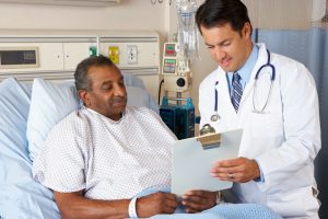 Doctor explaining something on clipboard to patient in bed