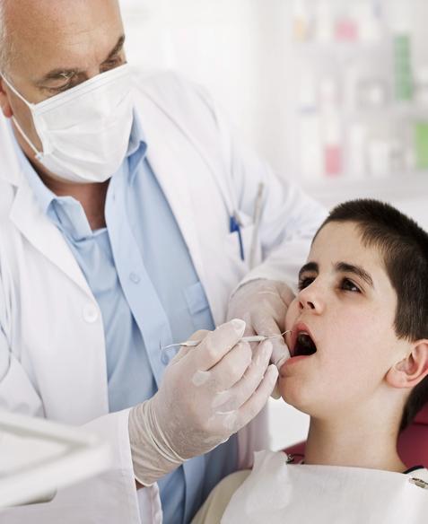 Dentist Wearing Mask Treating A Pediatric Patient