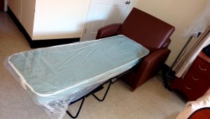 New mattress wrapped in plastic on foldout chair