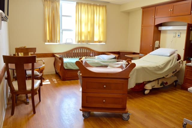 Maternity hospital room with bed, table and crib