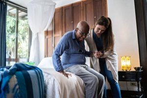 Caregiver helping patient out of bed