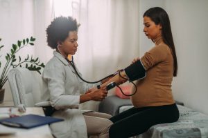 Doctor checking pregnant woman's blood pressure