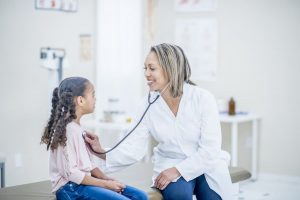 Doctor Checking The Heartbeat Of A Young Patient, Using A Stethoscope.